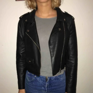  - Skinnjacka som slutar i midjan. Dragkedja för att stänga jackan. 