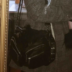  - Svart axelremsväska i läderimitation från Noella (modellen Celina). Liknar de trendiga väskorna från nunoo bags. Köpt december 2018, fint skick. Köpte för 700 kr på two angels i Göteborg. Köparen står för frakt, kan även mötas upp i Karlstad. 