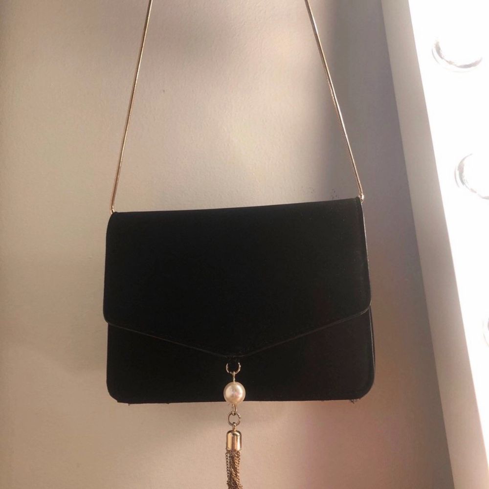 Fin liten svart axelväska med guld färgar band och detaljer. Accessoarer.