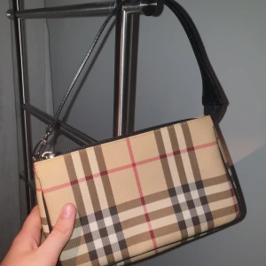Liten Burberry-väska - Köpt Second Hand. En liten fläck som syns i visst ljus (syns inte på bild). Tror att det är äkta men vet inte säkert, dock av väldigt bra kvalitét. Oanvänd, har inte fått användning av den tyvärr. Superfin väska :) Buda