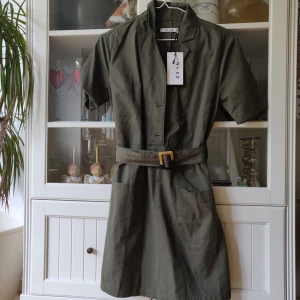 Supersnygg grön klänning i strl 34 - Jättefin grön klänning från Na-kd i storlek 34. Älskar verkligen denna så säljs endast vid bra bud. Aldrig använd då jag har en likadan i en annan färg!! 🥰🥰 Sitter jättefint och går att knyta i midjan. Nypris: 499kr. Buda från 150kr