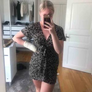  - Somrig, fin och trendig klänning med knytning under brösten för en fin form. Skönt material som andas. Svart med beige/vita blommor. !!!! Buda!!!! Startbud- 70kr (säljer inte om jag inte blir nöjd med pris) 