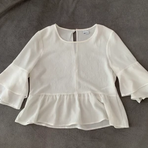 blus från Ginatricot  - Jättefin blus med volanger från Gina, sparsamt använd. Går att klä upp och ner och passar tex till midsommar.  Köparen står för frakten. 