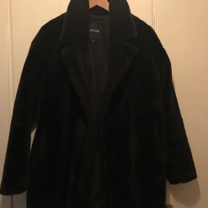 Jacka fuskpäls storlek xs - Svart jacka med fuskpäls/”ludd” från Monki. Storlek xs men passar s. Sparsamt använd.