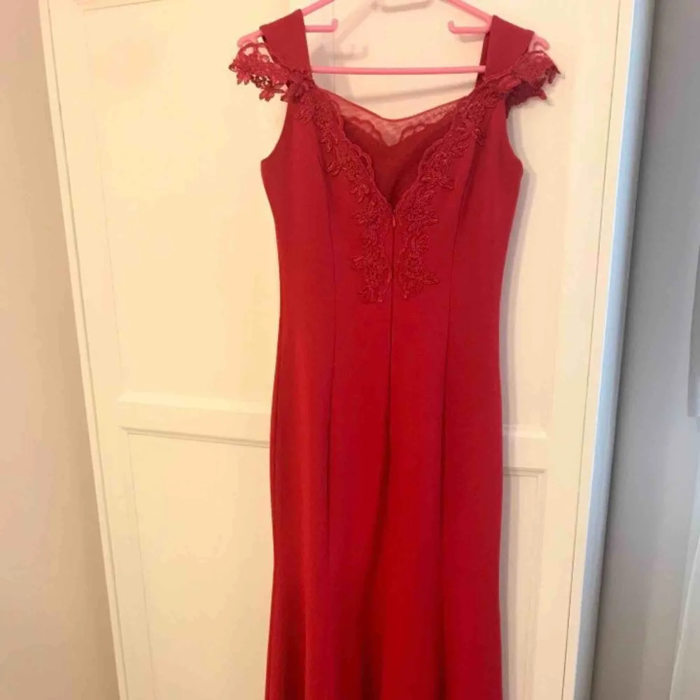 Röd lång klänning med fina blomdetaljer med en extra sydd transparent tyg på baksidan. XS i storlek och använd bara 1 gång på bröllop. Frakt eller mötas upp kan diskuteras.. Klänningar.