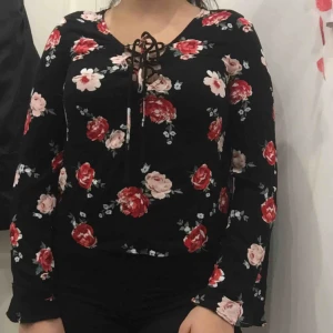 - Riktigt skön samt snygg tröja med fina blommor, perfekt nu när våren närmar sig!  Den har som en urringning med snören som man kan ”justera”. Den har även som jättesmal flärp längst ned på slutet av armarna vid händerna. 