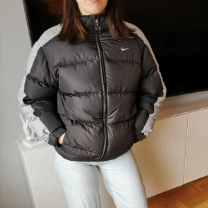 Nike jacka  - Retro vinterjacka från Nike, storlek 174 men skulle mer säga att den motsvarar S-M. Jackan är svart och grå. Finns en luva som man kan välja om man vill ha på eller inte. Bud under bilden🌺