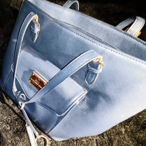 NYPD handväska  - NYPD handväska 2 småfack (för tex mobil lite smink kortetui och ett större med dragkedja, även ett fack på utsidan av väskan. Väskan är som ny men jag har lyckats få fläckar från ett läppstick i fodret 😳 inget som färgar av sig o det syns ju inte från utsidan 😉 något skavd på remmen där "trassel grejen" sitter. 