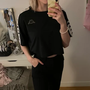 Kappa t-shirt  - Svart Kappa t-shirt i en kortare modell. Materialet liknar det på badkläder vilket gör den stretchig och otroligt bekväm. Använd några gånger.