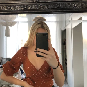 Blus - Brun och prickig blus från ginatricot, endast använd 2/3 gånger så i väldigt bra skick. Knyter den i midjan och ger väldigt fin siluett. Köparen står för frakt (spårbar), jag står ej för postnords slarv🤎