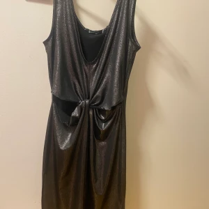 Festklänning - Säljer en festklänning i färgen silver, den har en öppning vid magen som en knut. Är i storlek S och köpt från bubbleroom. Använt vid ett tillfälle annars som oanvänd. Säljer för 150kr. Frakt tillkommer!