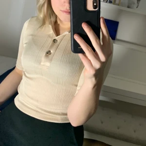 Ribbad champagnefärgad topp från NAKD - En jättefin ribbad champagnefärgad topp från NAKD med guldknappar✨💞 Oanvänd, Storlek XS och säljer pga fel storlek. Köparen står för frakten,45 kr, eller så kan jag mötas upp i Gävle📍💌😊 Pris 70 exklusive frakt