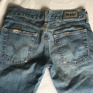 LEVIS Jeans - Lågmidjade vintage jeans från Levi’s med röda streck. Rak modell/ lite vidare under låret