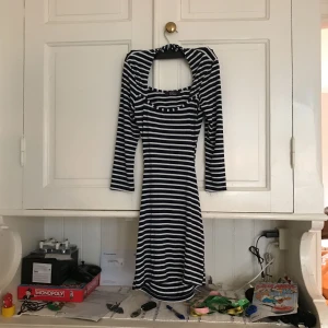  - Randig klänning från Rare Nelly, öppen på sidorna och ryggen, sitter tight, kommer ner till mitten av låren Superstretch 