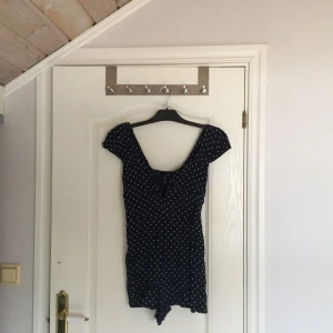  - Ny mörkblå jumpsuit med vita prickar. En roset över bysten som är fast sydd (se bild 1). Jumpsuiten är mycket kort i modellen jag har storlek 38 i vanliga fall och denna jumpsuiten är storlek 40 och den är för liten för mig. Inköpt i somras aldrig använd.
