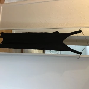  - Svart klänning med kort slits nedtill, sidenliknande tyg och fin passform. Obs skrynklig på bilden! 