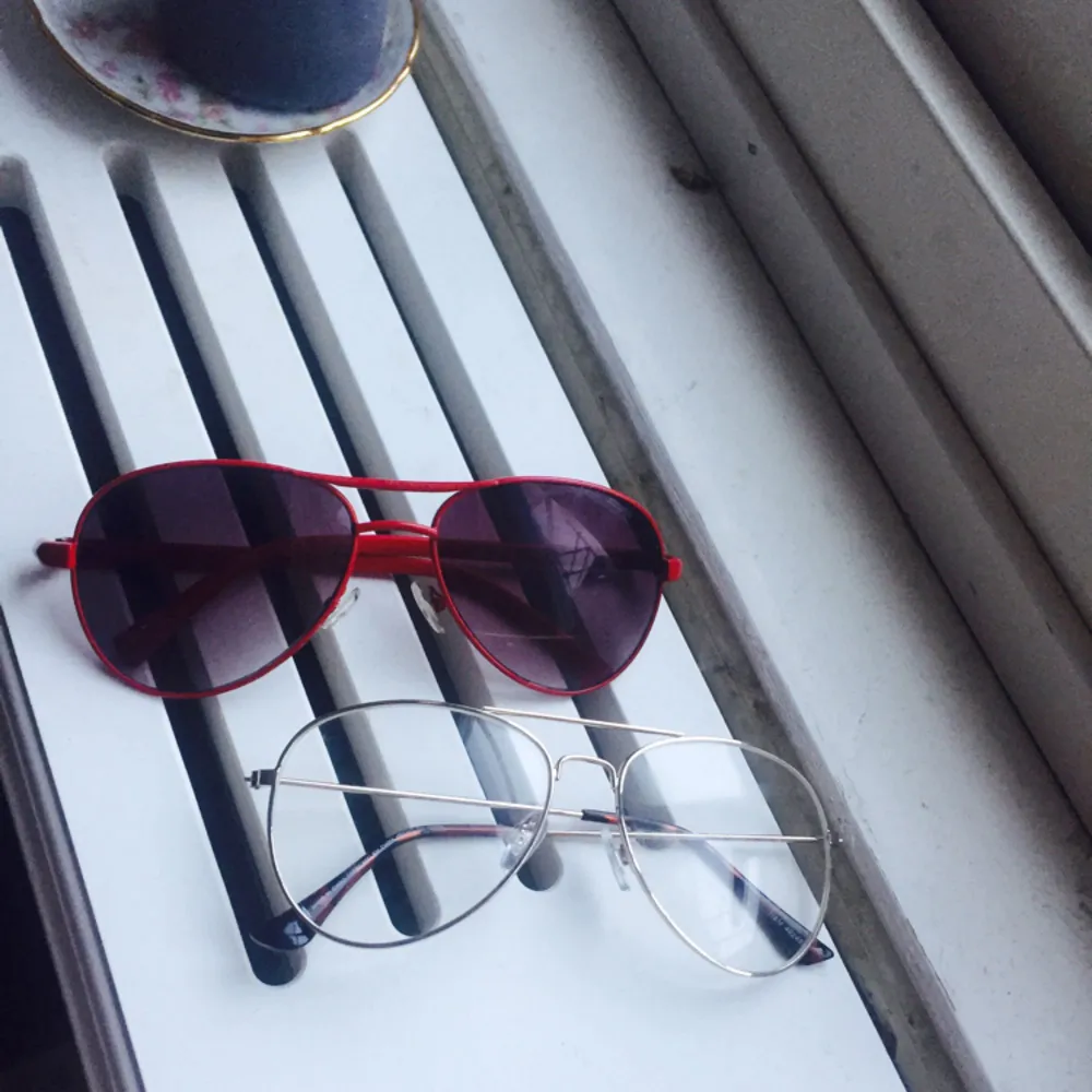 Två par jättesnygga glasögon, den röda är solglasögon med bågar i metall, och den andra är glasögon färgen är silver i pilotmodell med metallbågar. Klarglas.. Övrigt.