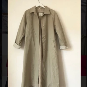  - Beige/grå tunn kappa med prickigt innerfoder i sidenaktigt material. Färgen är som en blandning av första och sista bilden. Storlek 42 men passar säkerligen mindre storlekar också.