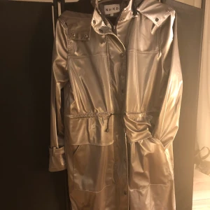 Na-kd regnjacka  - Jackan är som ny.  Modern silvermetallfärg, ser väldigt bra ut.  Storlek s, men motsvarar också m.