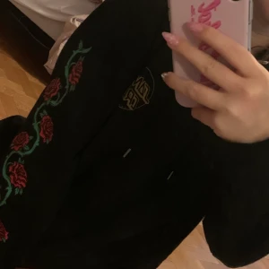Santa Cruz Hoodie  - Svart Santa Cruz Hoodie med rosor på armarna. Storlek 12 står det men skulle säga S. 