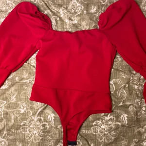 Röd body storlek M. - En väldigt skrik röd fancy body med lite tjockare material. Storlek M (S funkar också). I nytt skick.