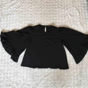  - Svart blus från Zara basic collection med vidare ärmar och volang. I ryggen finns en knapp som går att se på bild 2.  Använd en gång.  Kan mötas upp alt. skicka.