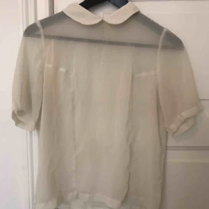  - Transparent topp från H&m. Söt krage som är fin att ha under tjocktröjor. Inga hål eller fläckar men en tråddragning i ena armhålan (se bild). Strl S  Finns att hämta i stockholm, annars tillkommer frakt 