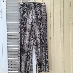Ormskinnsbyxor högmidjade beige svart M - Ett par högmidjade ormskinnsbyxor i skönt stretchmaterial som behöver nytt hem. I utmärkt skick! St 38/40. 