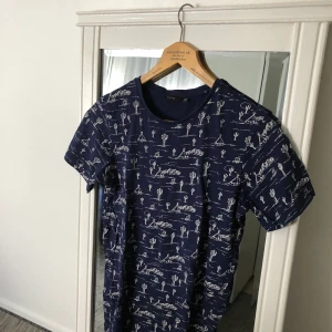 Blå t-shirt  - Blå t-shirt med vita mönster i storlek S (man storlek). Använt ett par gånger, fortfarande i bra skick. Frakt förekommer, men kan mötas upp i Göteborg. För fler frågor och bilder kontakta mig!