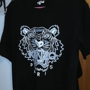 Kenzo t-shirt  - Ny kenzo t-shirt, endast testad en gång. Jättebra skick, kan bjuda på frakten.  300 kr eller bud. Den är strl L och passar vem som helst beroende på hur man vill ha den. 
