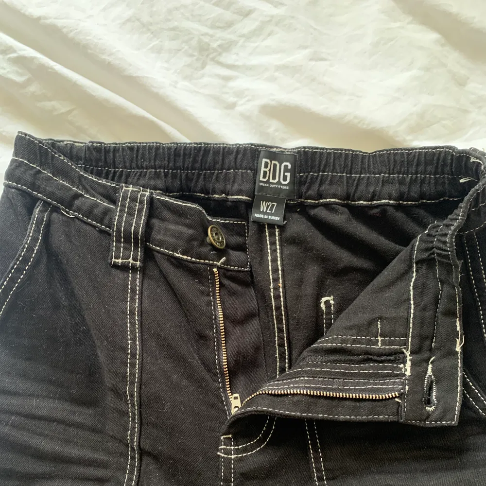 Skitsnygga svarta byxor med 7 fickor och vita sömmar. Storlek 27 i midjan . Jeans & Byxor.