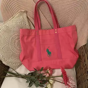 Denna väska är en Original Ralph Lauren Tote Bag i färgen rosa. Perfekt som en lyxig skolväska, strandväska eller shoppingbag då den är rymlig men ändå inte så jätte stor! Original pris ligger på 995 kronor. Denna är endast använd en gång.