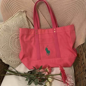  - Denna väska är en Original Ralph Lauren Tote Bag i färgen rosa. Perfekt som en lyxig skolväska, strandväska eller shoppingbag då den är rymlig men ändå inte så jätte stor! Original pris ligger på 995 kronor. Denna är endast använd en gång.
