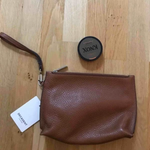  - Helt oanvänd handväska från Decadent. Tjockt brunt läder med dragkedja. Nypris 1865kr