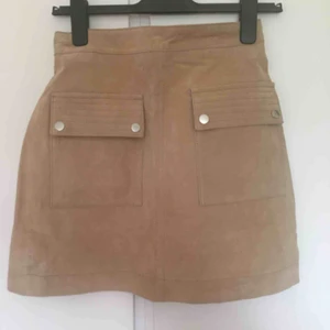 - Beige kjol i äkta mocka. Aldrig använd. Köpt på Mango, orginalpris 600 kr.   Kan mötas i Lund, Malmö el Staffanstorp, annars frakt som gäller :)