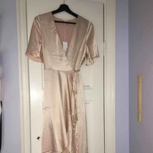  - Jättefin ljusrosa siden omlottklänning som aldrig är använd och har kvar alla lappar. Ej använd pga inte haft tillfälle. 