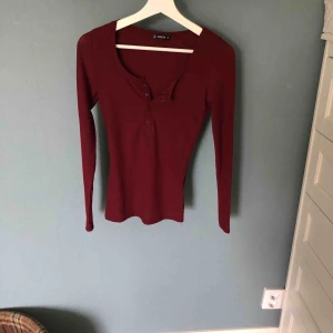  - Långärmad vinröd tröja med knappar, går att knäppa helavägen upp eller ha lite uppknäppt 