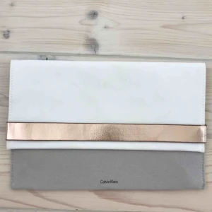  - Stilren clutch från Calvin Klein. Riktigt snygg i fina färger, perfekt till finare tillfällen som bröllop eller bal. Aldrig använd. 