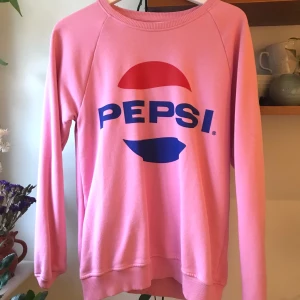 SWEET SKTBS Collegetröja  - Rosa collegetröja från Junkyard med 80-talets Pepsi logga. Storlek: Unisex S 