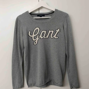 - Skön, stickad, långärmad tröja från gant med vit text. Knappt använd och därav i perfekt skick. Färgen är ljusgrå. 