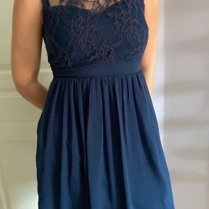Marinblå klänning med spets - Miniklänning från Vera Moda med spetsöverdel i strl S. Endast använd en gång och därmed i bra skick!