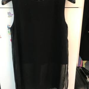 Svart tröja öppen på sidorna  - En svart ganska lång tröja med öppet på sidorna och ett svart linne under. Använd Max 2 ggr 