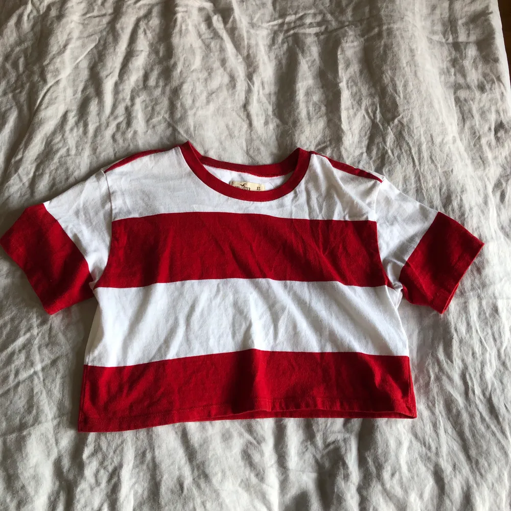 En rödvitrandig croppad T-shirt från Hollister. Knappast använd. Passar bra till det mesta och lätt att styla. Köparen står för frakten!. T-shirts.