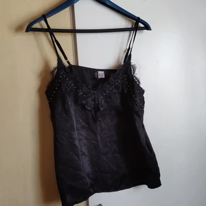 Svart spets linne från HM  - Tyget är typ glansigt och lent som siden eller satin,är inte så bra på tyger lol, spets i urringen med små silver detaljer. Banden är justerbara så passar de flesta storlekar