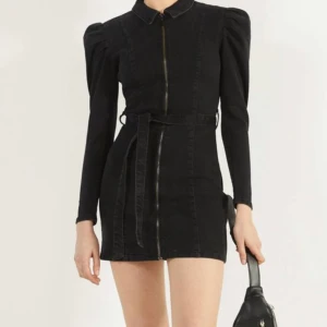 Svart denimklänning - Aldrig använd. Knytning i midjan, stretchig. Storlek L men jag är normalt en 38/40 och den passar perfekt. Passar även mindre men kommer inte vara lika tight runt ben och rumpa 