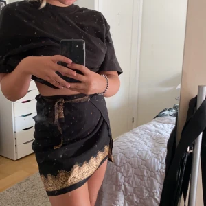 Kjol - Second hand kjol! Skitfin svart kjol med gulddetaljer. Går att bestämma storleken runt midjan så som man önskar.