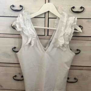  - Vit ärmlös topp med volanger på axlarna! Jättetrendig!!