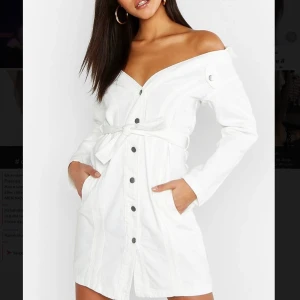 Tall Off The Shoulder Belted Denim Dress - Svinsnygg vit jeansklänning från BooHoo’. Helt oanvänd och säljs för att jag råkade beställa en storlek för liten. 