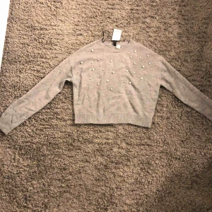  - en grå stickad tröja med lite pärlor, helt oanvänd