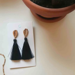 Örhängen  - Jätte fina och trendiga örhängen från hm. Guldiga snäckor med svarta fransar som är köpta i somras men har tyvärr aldrig kommit till användning☺️ (frakt tillkommer)